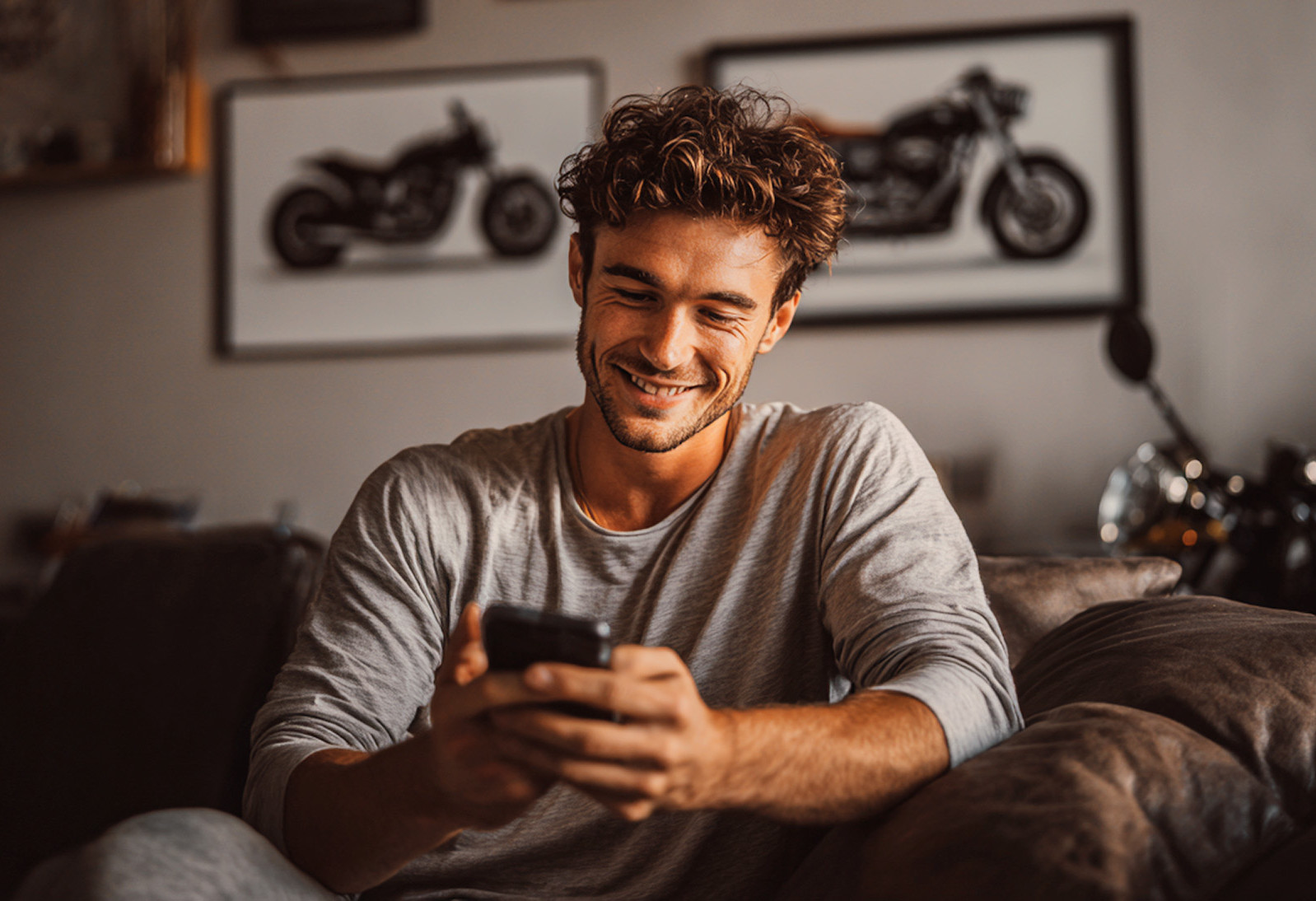 KI generiert: Eine Person mit lockigem Haar sitzt lässig auf einem Sofa und hält ein Tablet in den Händen. Im Hintergrund sind gerahmte Bilder und ein Regal mit Büchern und Deko-Objekten zu sehen.