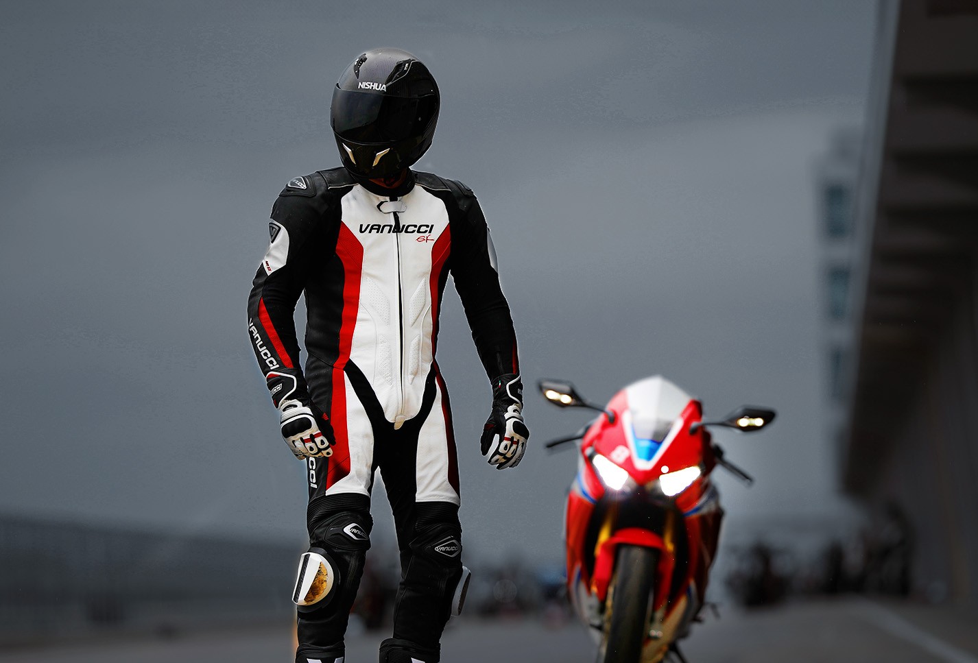 Motorradfahrer in Lederkombi vor einem Racing Motorrad