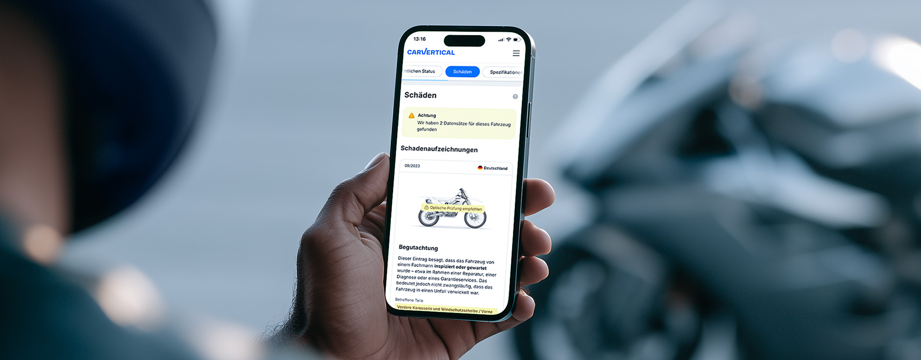 AI-gegenereerd: Hand die een smartphone vasthoudt met een app voor motorverzekeringen en schadeclaims, met op de achtergrond een motorfiets.