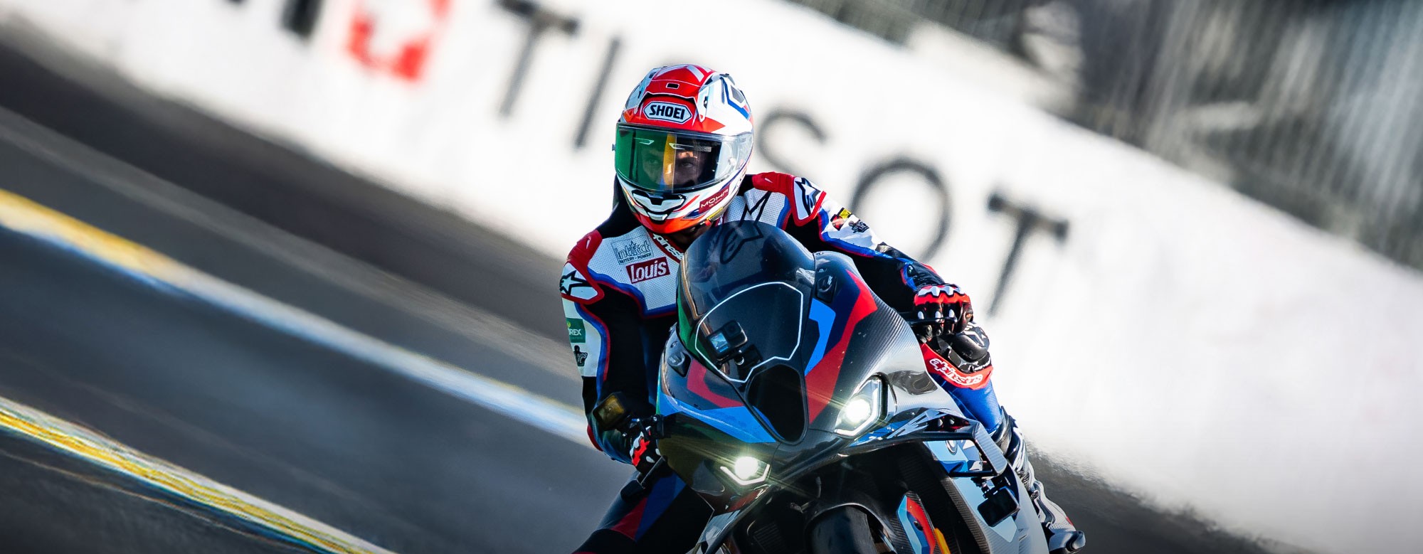 Alex Hofmann in Racing Bekleidung der auf einem Racing Motorrad um eine Kurve fährt