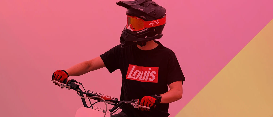 Person mit Motorradhelm auf Motorrad und schwarzem Louis‑T‑Shirt vor Farbverlauf mit Schriftzug ‚RIDE IT. LIVE IT. WEAR IT.