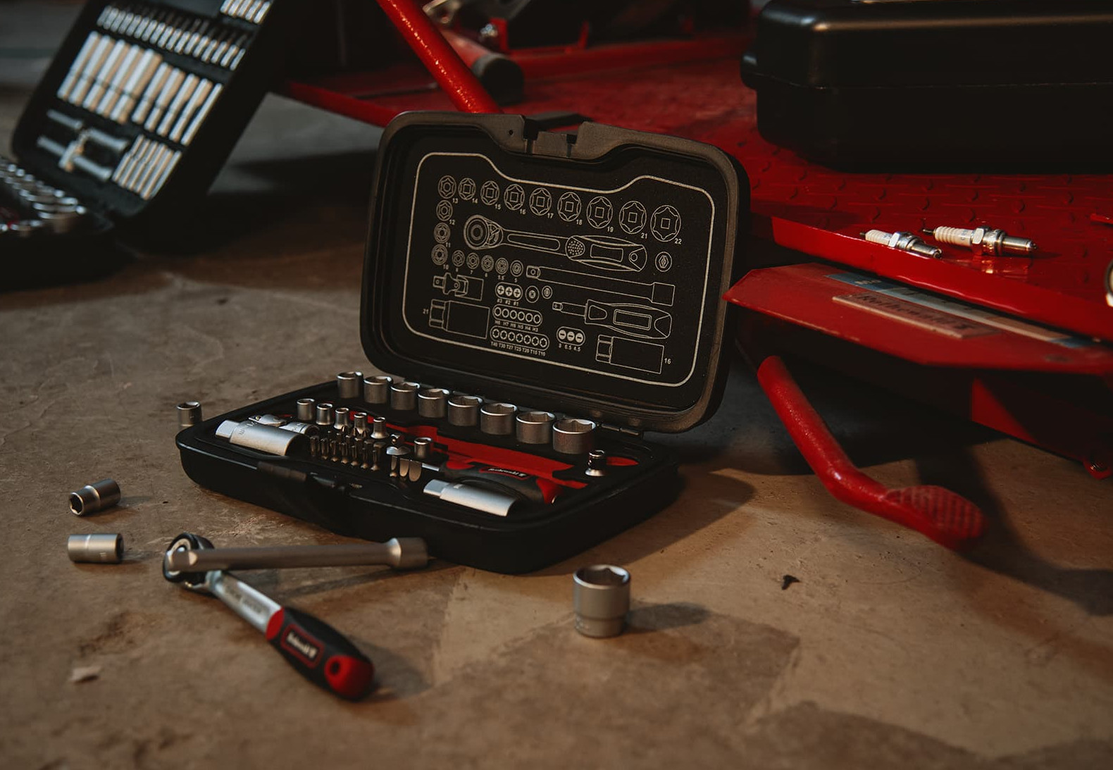 Werkzeugset und Motorrad-Zubehör auf einer Werkbank in Werkstattumgebung.