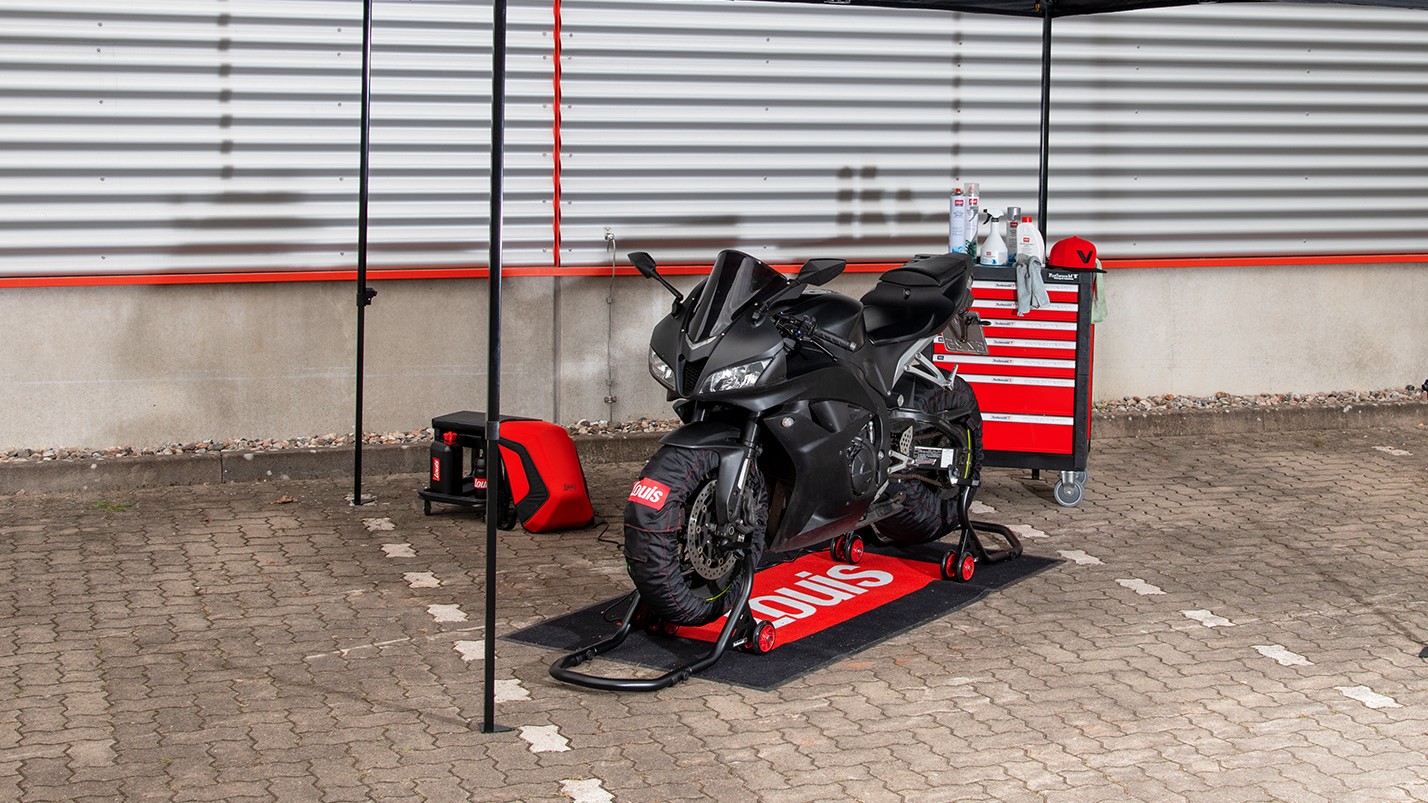 Ein Racing Motorrad unter einem Pavillon auf einer Motorrad Fußmatte mit Werkzeug im Hintergrund 