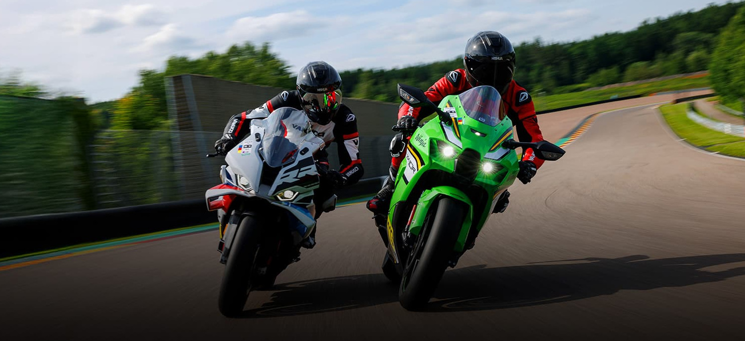 Zwei Motorradfahrer fahren auf einer Rennstrecken nebeneinander Motorrad